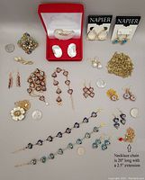 Lot of various fashion jewellery items spread on flat surface including earrings, bracelets, necklaces, brooches, and chains.