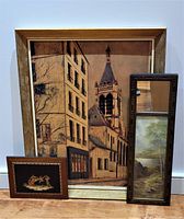 Lot of three items including a Maurice Utrillo framed print depicting a street with a church, an art deco style mirror and landscape frame, and a hand-painted inlaid wood wall plaque with musicians.
