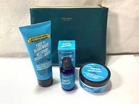 Beard care set items arranged in front of teal Shiseido travel pouch, showing Face & Beard Wash, Beard Oil, and Beard Balm.