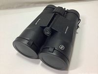 Black Bushnell binoculars with lens covers on, showing overall compact form and Bushnell branding.
