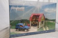 Playmobil Country themed exhibition display model showing a blue car and a garage with red roof inside clear plastic display case.