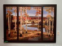 Front view of the three-panel acrylic print in a dark wood frame depicting a birch tree autumn landscape with river and blue sky.