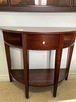 Front view of demi lune wood table showing drawer and lower shelf