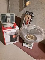 Holmes heater on top of Honeywell humidifier box and white fan on floor.