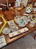 Wide view of various vintage glass figures and ceramic dish on wooden table