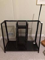 Full view of black metal golf club stand with mesh sides and one golf club inside