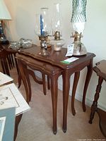 Two medium brown wood vintage nesting tables with curved legs and scalloped edges, empty on floor.