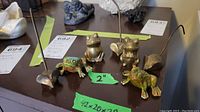 Overview of six animal figurines: two ceramic frogs and four brass mice and frogs.