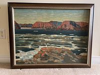 Photo of full framed print showing landscape scene with water and cliffs, in a wood frame with minor scratches.