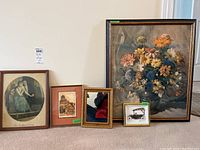Four framed items displayed on floor: two prints, a 3D car art made from watch parts, and a small framed mirror.