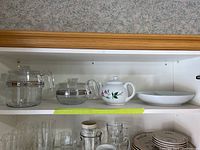 Shelf showing Pyrex retro glass coffee percolator, Christineholm floral tea pot, and Mikasa divided glass bowl, with additional glassware below.