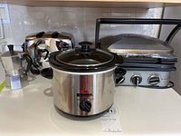 Photo showing four small kitchen appliances together on counter: Sunbeam toaster, Bialetti espresso maker, Kenmore slow cooker, and Cuisinart Griddler grill.