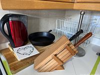 Photo shows two wood cutting boards, 12x20 and 14x10 inches, white tile with heart design, Brita water pitcher, cast iron fry pan, and racks on kitchen counter.