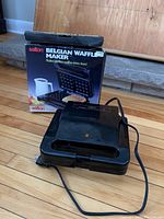 Salton Belgian Waffle Maker unit next to original box showing external view and branding.