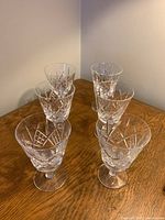 Six crystal glasses arranged on a wooden table, showing the group and design.