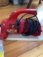 Red Dirt Devil Plus handheld vacuum with power cord coiled around it