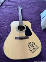 Front of Fender DJ10NAT acoustic guitar showing natural finish, black pickguard, Alexander Keith's India Pale Ale logo