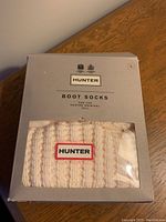 Front view of boxed Hunter boot socks showing knit texture and logo patch through clear window.