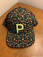 Full view of Puma hat showing multicolor icon pattern on black background and embroidered light green 'P' on front.