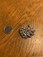 Brooch placed on a wooden surface next to a quarter for size reference