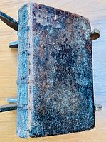 Top view of antique book showing worn leather binding and metal clasp edges.