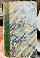 Cover showing marbled paper with green leather spine, edges worn with some chipping at corners.
