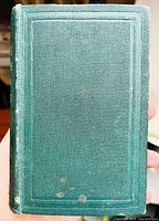 Green textured hardcover front cover with decorative border, minor wear and small spots visible.