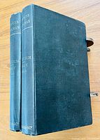 Front view of two hardcover volumes showing green cloth covers with gilt titles on spine and some age wear.