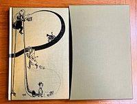 The hardcover book with illustrated beige cloth cover and protective slipcase shown together.