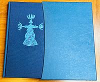 Dark blue hardcover book with light blue emblem on front and matching slipcase
