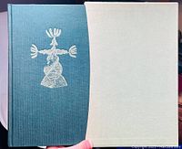 Photo of the front cover featuring green cloth with silver embossed illustration.
