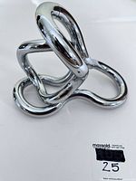 Angled top-down view of the chrome loops assembled in a compact configuration with MaxSold lot sticker visible