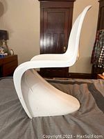 Side view of the white molded fiberglass chair showing its continuous flowing form and profile.