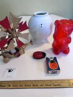 Overview of all lot items on white surface: wooden mobile, white vase, red gummy lamp, ladybug flashlight and box