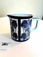 Side view of ceramic pitcher showing blue fruit pattern and handle