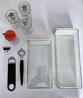 Overview of all items: three clear lucite grinders, one red grinder, two Rosti canisters, one black metal and plastic opener, one mid-century Japanese bottle opener.