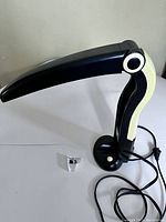 Lamp unfolded, side view showing black and ivory plastic folding design with power cord visible