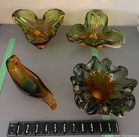 Four amber to green gradient glass decorative items arranged on gray surface