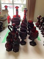 Wide shot of lot showing eight wine goblets, two large goblets, vases, cruets, and salt and pepper shakers in rich ruby red Cape Cod pattern glass