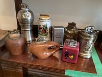 Group photo of all 7 table lighters showing various sizes, materials, and designs on a wooden surface