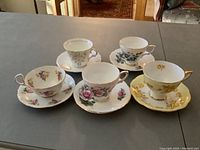 Five bone china tea cup and saucer sets each with unique floral patterns displayed on table