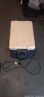 Full view of Coleman electric cooler with white lid and gray body, showing attached motor cooler and power cord.