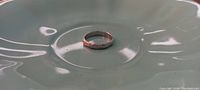 Front view of platinum ring with solitaire diamond on ceramic dish