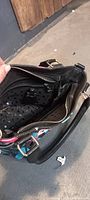 Interior view of black purse showing zippered compartment and perforated inner lining