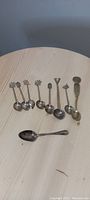 Full set of eight spoons arranged on table showing different handle designs and bowl shapes