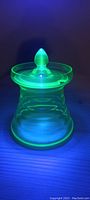 Uranium glass sugar bowl lit under 395 nm UV light showing bright green glow characteristic of uranium.