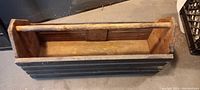 Top view of rectangular wooden tool box showing interior and handle, highlighting used condition and paint detail.