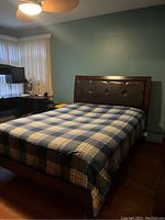 Bed frame in bedroom setting showing wooden frame, upholstered headboard, and bedspread.