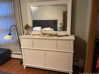 Front view of white wooden dresser with five drawers and large mirror