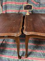 Top view of two matching wooden side tables showcasing curved edges and surface scratches.